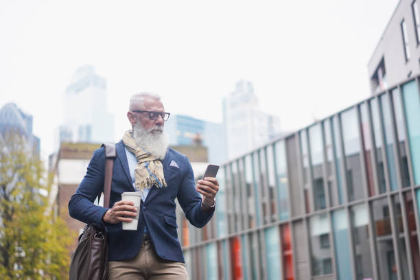 istock Senior hipster man using mobile phone and drinking coffee on the city - Focus on face 1284385088
