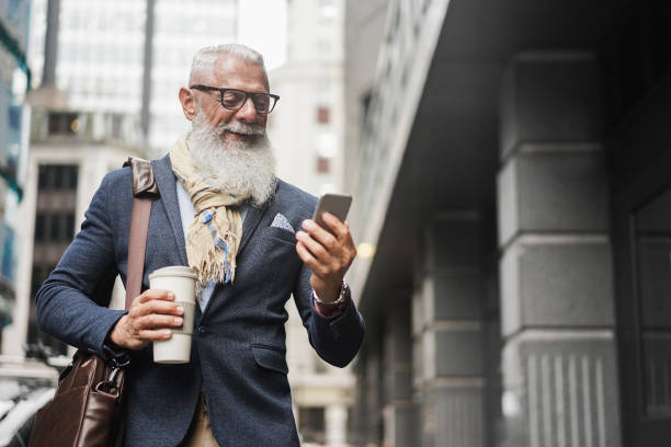 istock Senior business man using smartphone app walking to work - Entrepreneur drinking coffee while going to office - Job, business, elegant, fashion and confident concept - Focus on face 1284385111