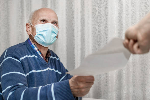 senior man wearing protective face mask taking paper sheet with recipe from doctor hand senior man wearing protective face mask taking paper sheet with recipe from doctor hand inside demobilization photos stock pictures, royalty-free photos & images