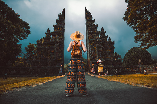 Traveller woman posing in front of a temple in Bali, Indonesia. Woman with backpack on a trip in Asia