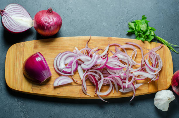 istock Red onion sliced. The process of cooking on a yellow cutting Board. Flat top view 1284391681