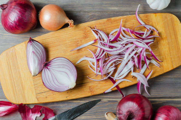 istock Red onion sliced. The process of cooking on a yellow cutting Board. Flat top view 1284391685
