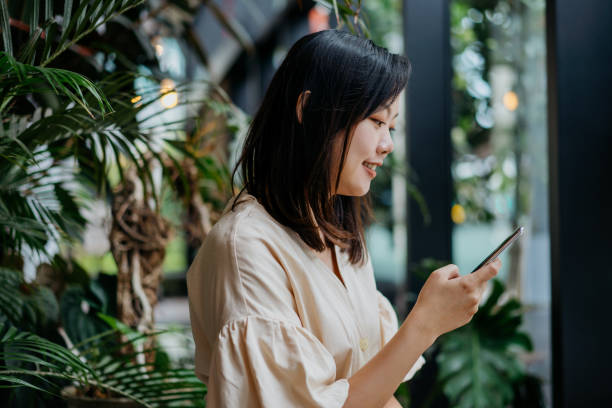 istock Smiling young asian woman using smartphone in a cafe 1284393881