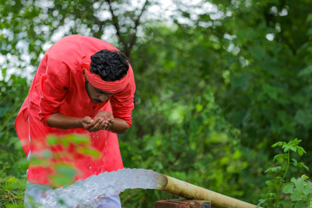 istock Indian farmer drinking water with hand from pipeline at field 1284394116