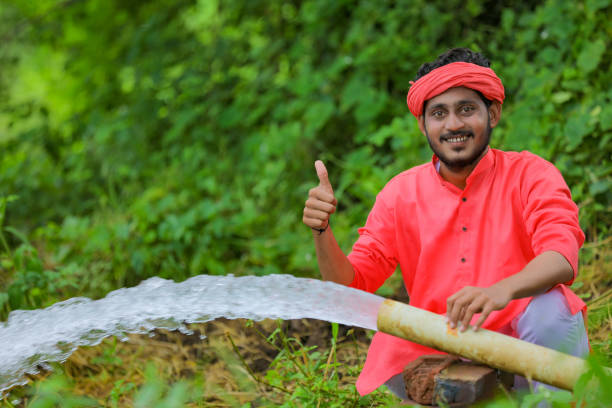 indian farmer with water flow from pipe at field