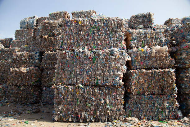 istock Close-up of compressed plastic gathered into bundles and stacked outdoors at waste management facility. 1284395418