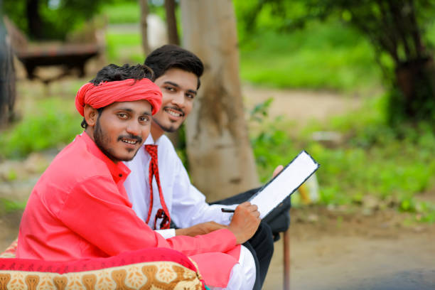 istock Young indian farmer sign on document with banker at home 1284398408