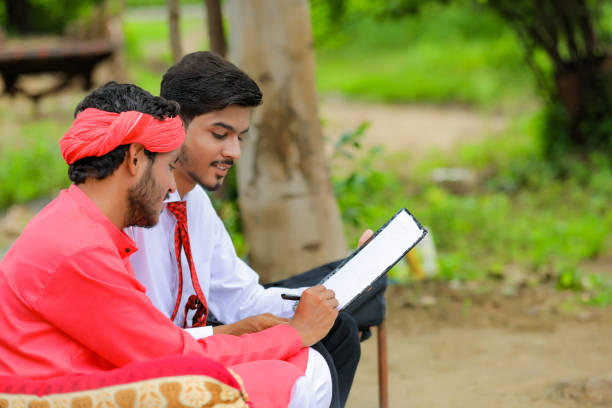 istock Young indian farmer sign on document with banker at home 1284398557