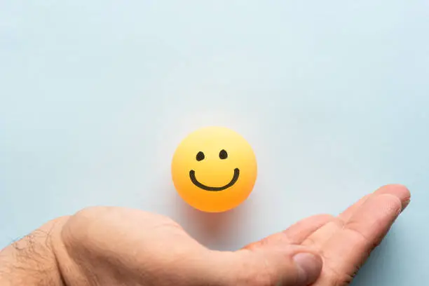 Photo of Close-Up Of hand palm showing drawing of happy yellow emoticon smiley face