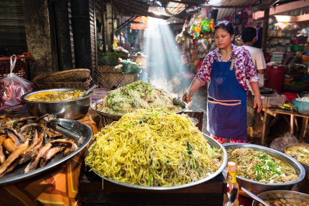 bild einer khmer landfrauen auf dem land, die straßennahrung auf einem offenen markt in kambodscha verkauft. - khmer stock-fotos und bilder