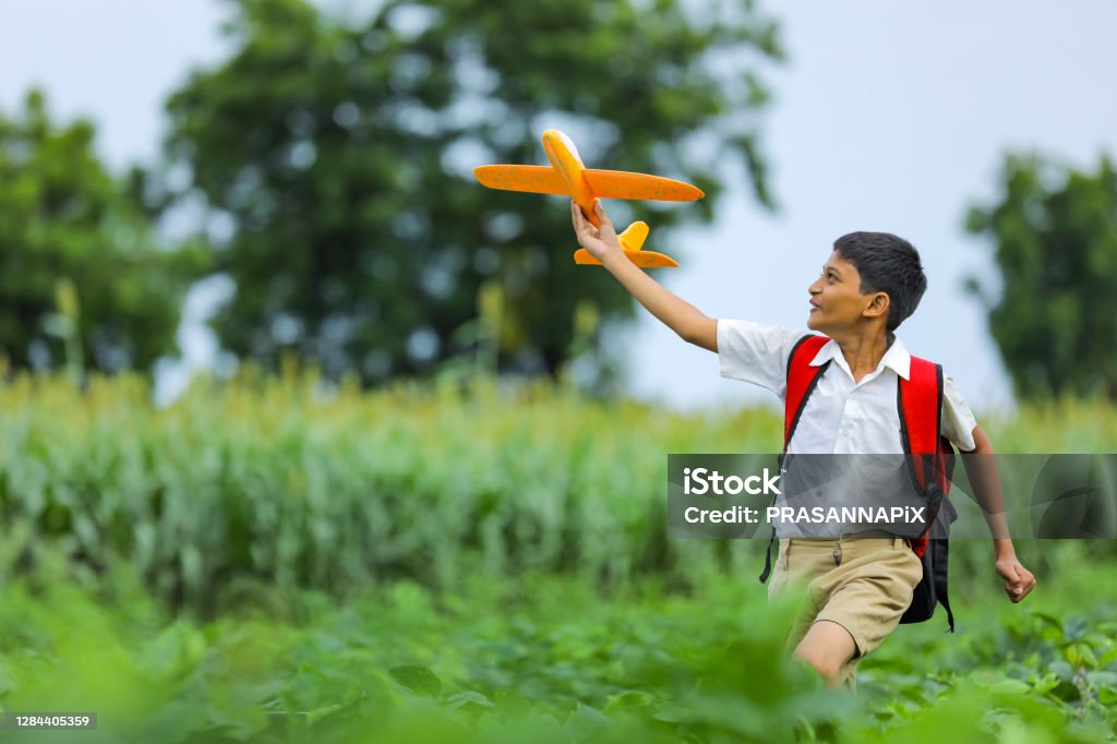 dreams of flight! indian child playing with toy airplane at green field Boys Stock Photo