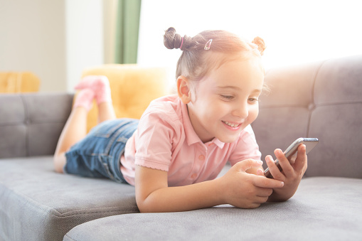 Little girl with mobile phone on couch