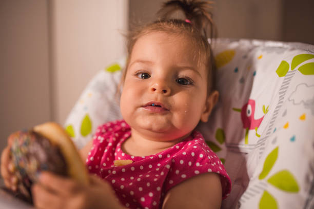 istock Messy baby girl eating chocolate sprinkled doughnuts 1284407936