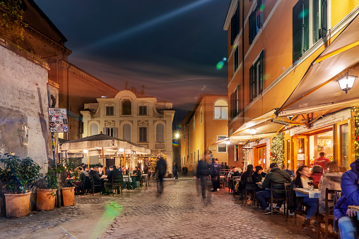 People relaxing at a pavement cafe on the streets in Trastevere,Rome. Families and groups of people eating, drinking and chatting.