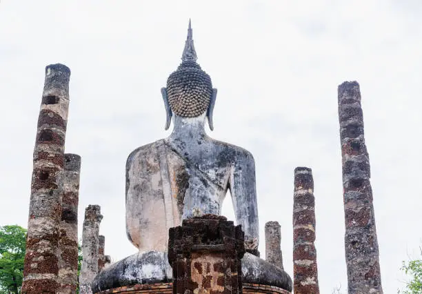 Photo of Back view of Ancient Buddha image with the ruins of temple at Sukhotai Historical Park, Sukhothai Historical Park is the UNESCO world heritage and Famous Tourist Destination in Northern Thailand