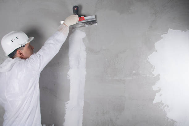 istock a master in a protective uniform and a hard hat, closes a crack in the wall with a white mixture, there is a place for the inscription 1284411022