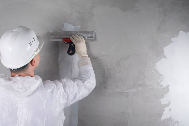istock master in protective uniform and hard hat, closes a crack in the wall with a white mixture, there is a place for the inscription, rear view 1284412728
