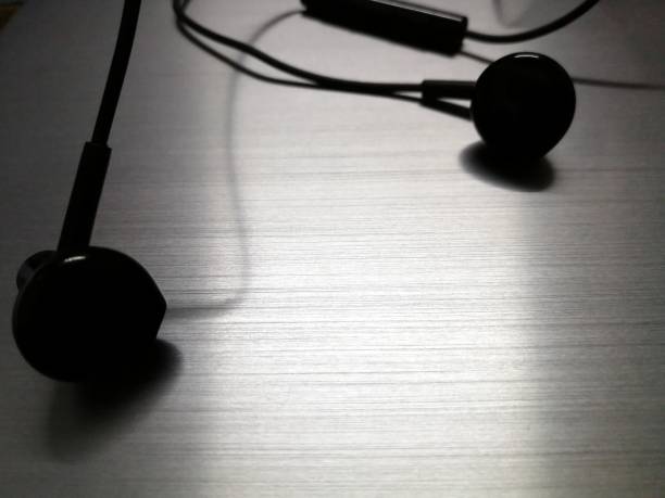 istock Black earphones on metal background 1284412956