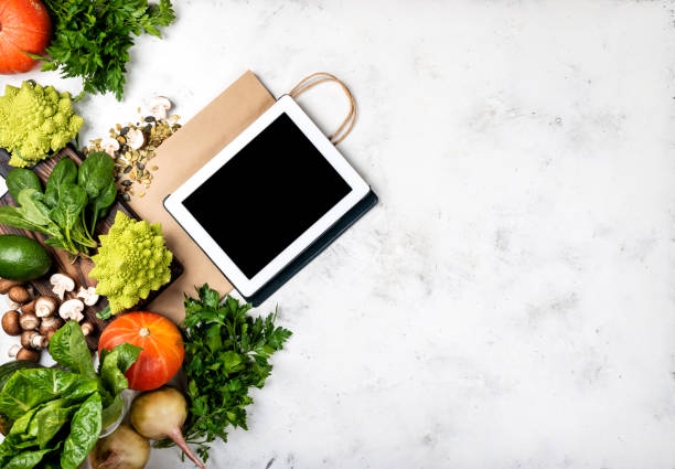 istock Online grocery shop concept. Tablet computer and shopping paper bag with different vegetables and greens. Top view 1284413841