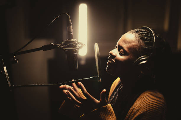 istock Black female singer singing into microphone in recording studio 1284415138