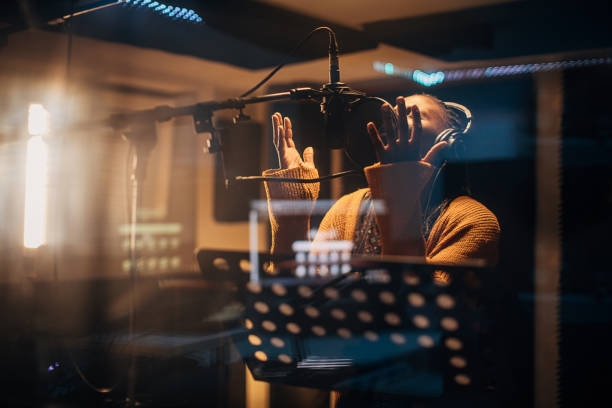 istock Black female singer singing into microphone in recording studio 1284415180