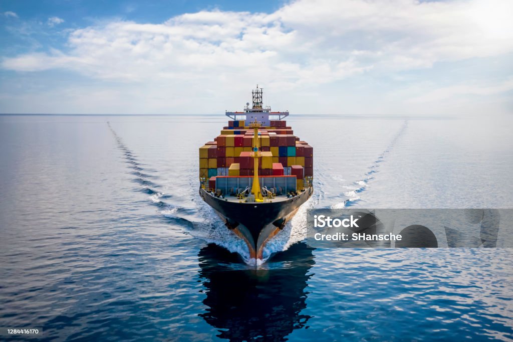 Aerial front view of a loaded container cargo vessel Aerial front view of a loaded container cargo vessel traveling over calm ocean Freight Transportation Stock Photo