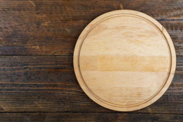 istock Round cutting board on a wooden table. Space for text. 1284417642