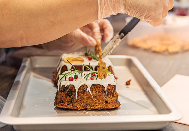 mains de femme décorant le gâteau de fruit de noël avec des biscuits de pain d’épice, le romarin et le lingonberry. - baking cake making women photos et images de collection