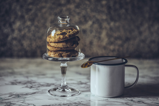 A stack of chocolate chip cookies, a jug of milk and textiles.