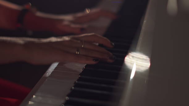istock A female young hands playing piano in black manicure and accessories. Classical music pattern. Girl playing piano keywords 1284420977