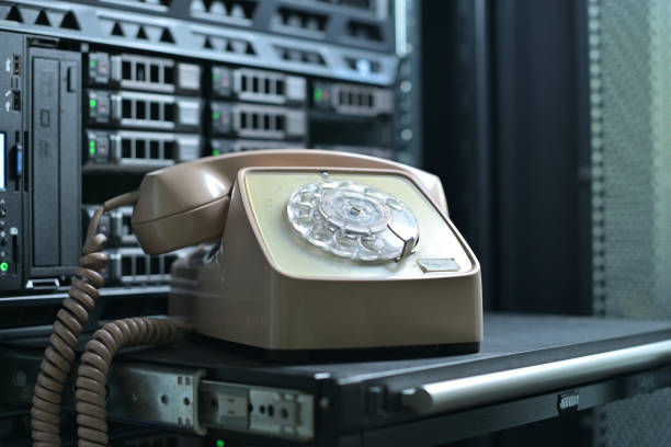 istock rotary phone, which stands against background of a server cabinet 1284424969