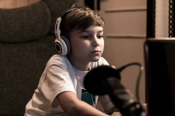 istock Little boy with headphones using laptop at night at home. 1284425470