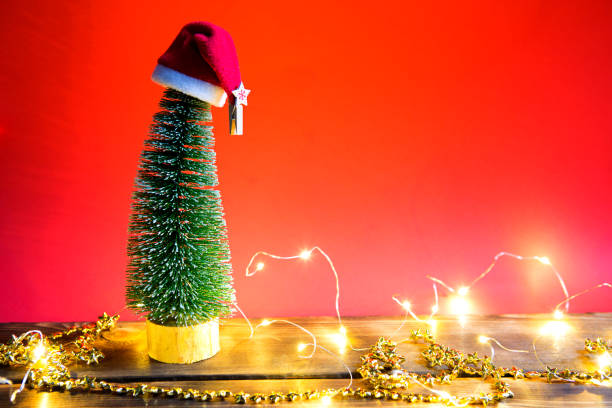 arbre de noël sur un fond rouge avec des lumières de guirlandes, canne rayée de caramel, chapeau de santa, tinsel. - christmas crutch holiday christmas decoration photos et images de collection