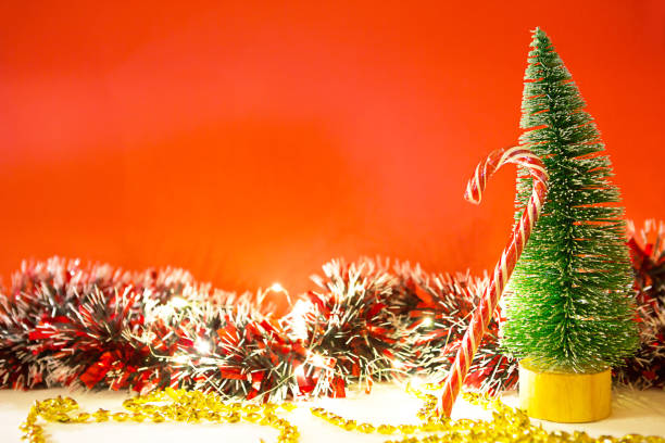 choinka na czerwonym tle ze światłami girland, karmelu paski trztówny, kapelusz santa, blichtr. - christmas crutch holiday christmas decoration zdjęcia i obrazy z banku zdjęć