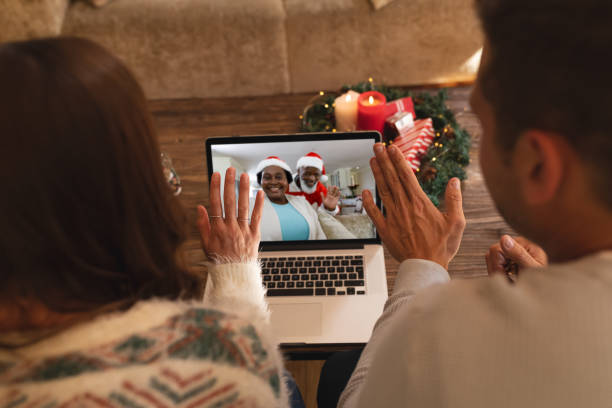 vista trasera de pareja saludando mientras tiene un videocall con santa claus y mujer mayor en santa sombrero o - santa claus waving christmas photography fotografías e imágenes de stock