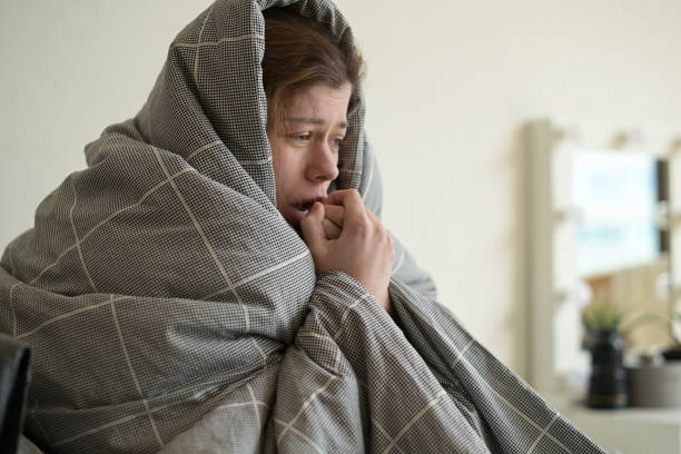 istock A woman is freezing and wrapped in a blanket in bed to keep warm 1284430009