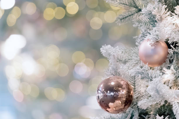 istock Decorated and illuminated christmas tree on blur bokeh background. Golden baubles on fir tree branch with defocused lights on backdrop. Happy new year or merry christmas postcard. 1284432514