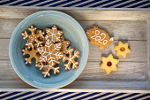 Various shapes of Christmas gingerbread cookies on light blue bowl on wooden table, group of simplicity winter sweets, pf 2020