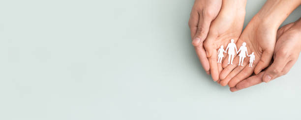 istock Family care concept. Hands with paper silhouette on table. 1284435820