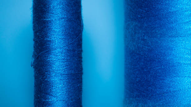 istock Background with a large and small blue spool of thread. They lie next to each other on a blue background 1284438101