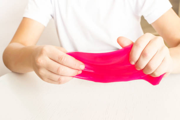 istock Modern toy called slime. Child playing transparent pink slime. Hands holding a mucus on a white background. Selective focus. 1284439277