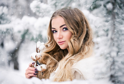 Winter bride in a snowy forest with a cotton branch. The concept of beauty and winter wedding.