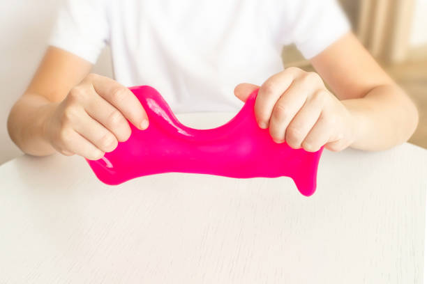 istock Modern toy called slime. Child playing transparent pink slime. Hands holding a mucus on a white background. Selective focus. 1284439458