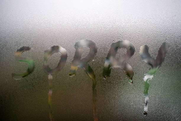 Conceptual sorry word handwritten message on the rainy glass window background. stock photo