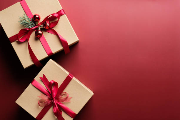 istock Gift boxes with red ribbon bow on marsala red background with copy space. Christmas presents, gift boxes, surprises concept. Flat lay, top view. 1284439637