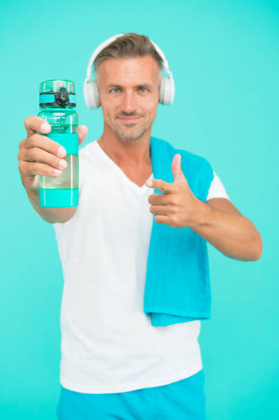 istock Drink water avoid thirst. Thirsty sportsman point at water bottle. Selective focus. Fit man advertise bottle to quench thirst. Thirst quenching during training or workout. Thirst and dehydration 1284440500