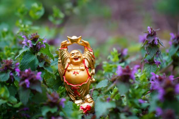 istock Smiling Buddha statuette in wild flowers. 1284441591