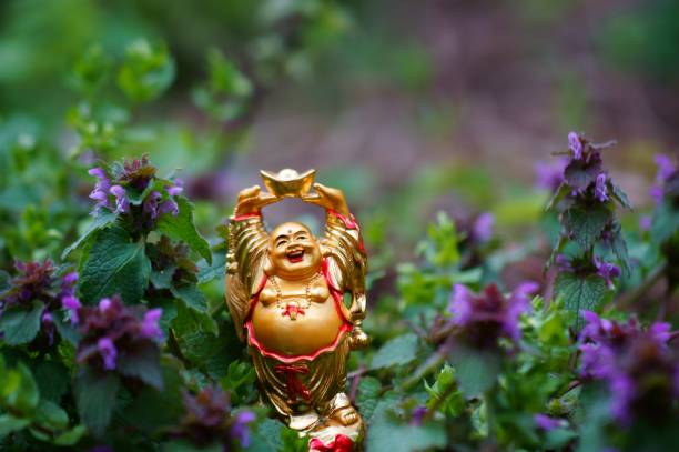 istock Smiling Buddha statuette in wild flowers. 1284441649