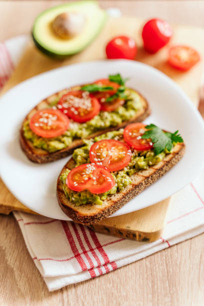 istock toasted bread with avocado paste and fresh tomato. Avocado mixed with lemon juice is spread on bread.  health food concept, vegan, vegetarian 1284442840