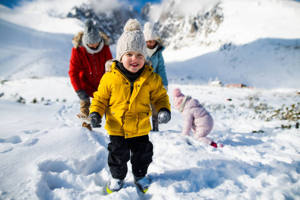 Small boy with family in winter nature, walking in the snow. Small boy with family in winter nature, walking in the snow and looking at camera. kids winter coat stock pictures, royalty-free photos & images